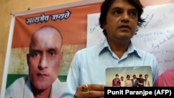 FILE: Indian friends of Kulbhushan Jadhav hold a photograph of them with Jadhav in the neighborhood where he grew up in Mumbai.