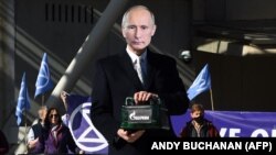 Активіст групи Extinction Rebellion у масці із зображенням президента Росії Володимира Путіна тримає контейнер з паливом під брендом «Газпром» під час акції проти використання викопного палива біля будівлі парламенту Шотландії. Единбург, 1 квітня 2022 року 