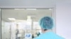 Belarus - Back of a man surgeon looking through glass at the operating room in hospital. Closeup. Undated