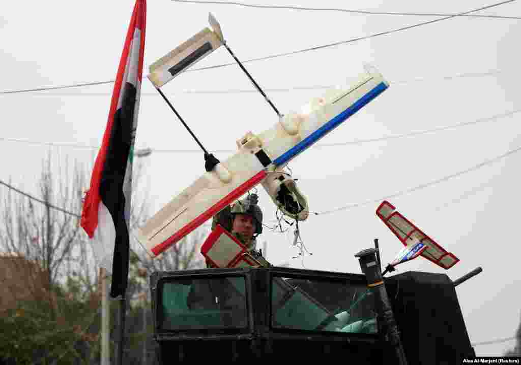 An Iraqi soldier carries a radio-controlled aircraft left behind by retreating IS fighters in Mosul. Small, commercially available craft like this have been loaded with explosives and used to launch airborne attacks on coalition forces.