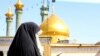 A veiled woman is seen in Qom, with golden-domed mosque in the background. File photo