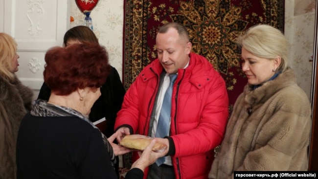 Депутат горсовета Керчи Вадим Кутузов вручает хлеб блокаднице