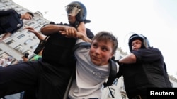 Полицейские задерживают мальчика во время акции протеста в Москве