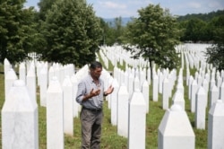Ramiz Nukic prays near the graves of his father and two brothers in the Srebrenica-Potocari Memorial.