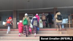 Девочки в платках в сопровождении родителей на входе в школу.