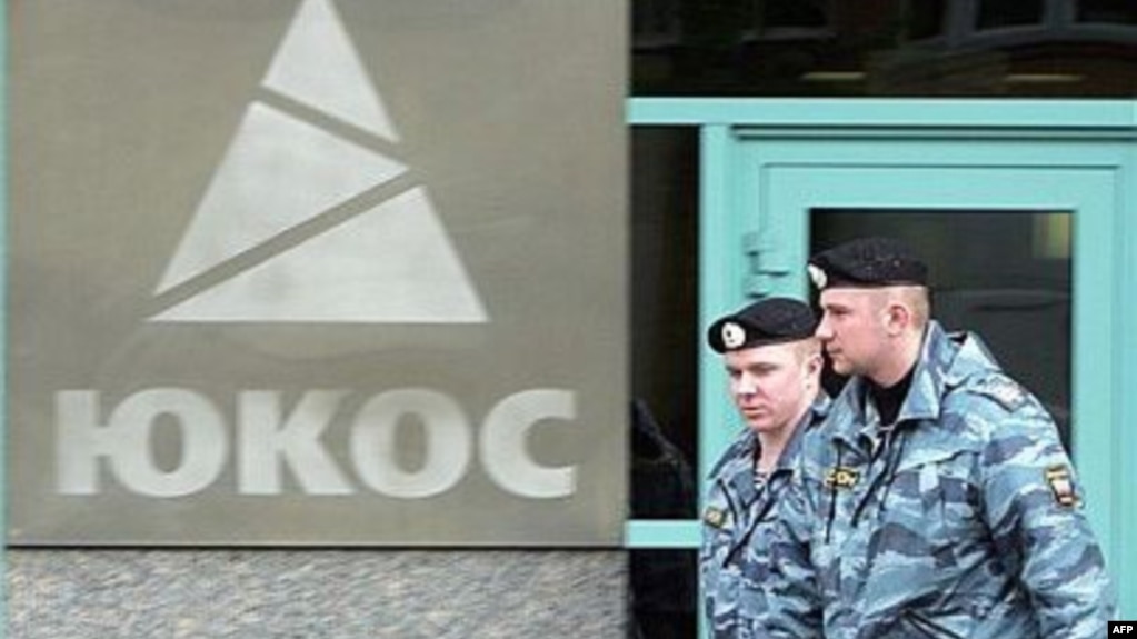 Two Russian policemen pass by the Yukos oil giant's logo during the controversial auctioning of some of the company's key assets at its headquarters in 2007. (file photo)