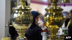 A woman prepares tea at a booth representing Iran at the 49th International Tourism Fair (ITB Berlin 2015) in Berlin on March 4, 2015.