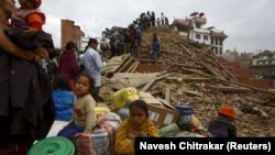 People sit with their belongings outside a damaged temple in Bashantapur Durbar Square after a major earthquake hit Kathmandu, Nepal, on April 25.