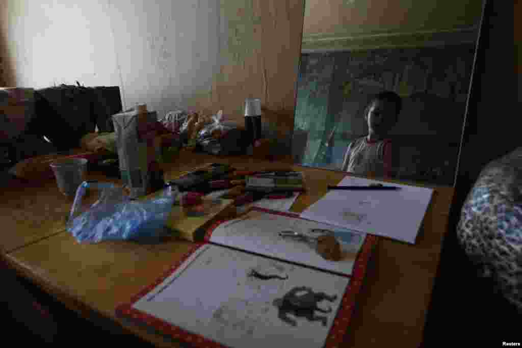 A child from a family who has fled from fighting in Slovyansk is seen in a mirror at temporary accommodation in a dormitory in the town of Ilovaysk on June 3.