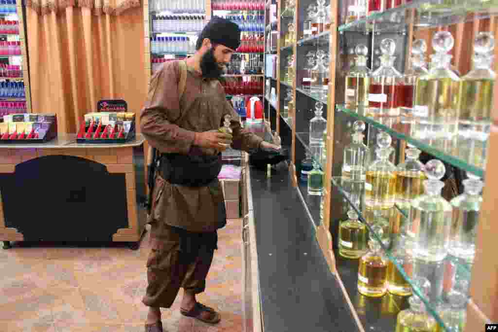A jihadist gunman looks at bottles of perfume at a cosmetic shop in the northern Syrian city of Raqqa. (AFP/Raqa Media Center/STR)