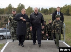 Президент Росії Володимир Путін (зліва) і його білоруський колега Олександр Лукашенко (справа) з його сином ідуть спостерігати за завершальним етапом спільних військових навчань «Захід-2013» на полігоні у Гродні, Білорусь, вересень 2013 року