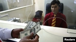 A customer counts his money after making a withdrawal at a branch of Aa bank in Kabul. (file photo)