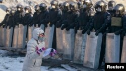 Женщина стоит на коленях перед милиционерами. Киев, 24 января 2014 года.