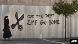 Жительница Афин на фоне граффити с призывом: "МВФ, убирайся домой", 20 февраля 2015