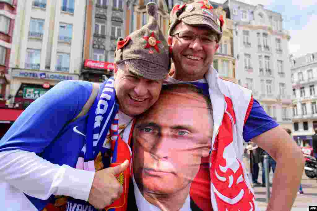Российский футбольный фанат позирует с приятелем, одетым в футболку с изображением президента России Владимира Путина в центре города Лилль, Франция, в преддверии матча между Россией и Словакией на чемпионате Евро-2016. Россия проиграла 2-1.(AFP/Leon Neal)