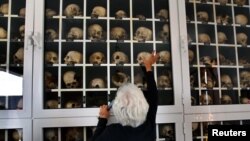 Survivor Panayiota Mario touches a glass panel containing the remains of victims of the Distomo massacre, committed by the Nazis during World War II in the village of Distomo, in Greece.