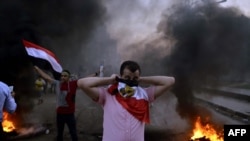 An Egyptian protestor covers his face with his national flag during clashes between supporters of Egypt's ousted President Muhammad Morsi and security forces in Cairo on August 30.