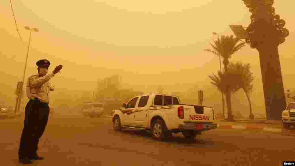A Iraqi traffic policeman directs vehicles during a sandstorm in Baghdad's Karrada district. (Reuters/Thaier al-Sudani)