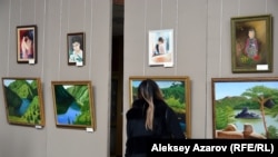 Карипбеку Куюкову более по душе рисовать пейзажи. Девушка рассматривает один из пейзажей художника. Алматы, 18 октября 2019 года.