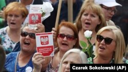Kormányellenes tüntetők kezükben a lengyel alkotmánnyal tiltakoznak az igazságügyi reform ellen a legfelsőbb bíróság előtt Varsóban 2018. július 4-én