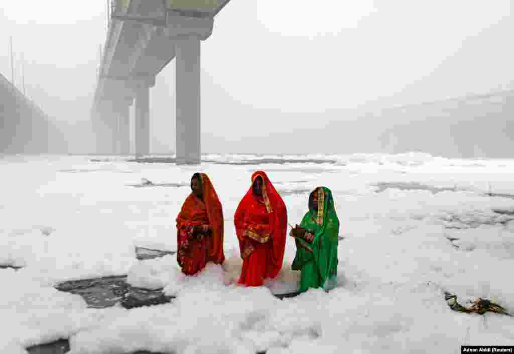 Hindu women worship the sun god in the polluted waters of the River Yamuna during the religious festival of Chatth Puja in New Delhi. (Reuters/Adnan Abidi)