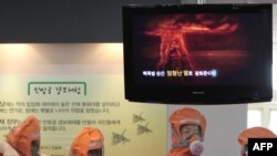 South Korean boys wearing masks listen to a government official explaining the effect of a nuclear bomb blast over the sky in a simulation room in Seoul.