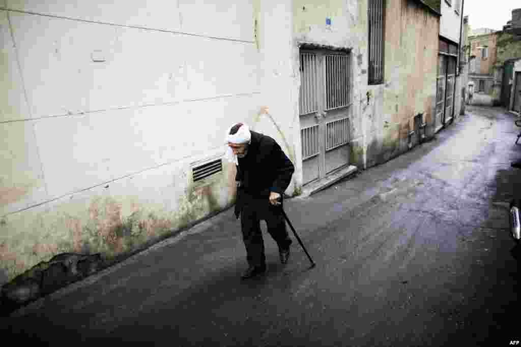 An elderly man walks down an alley south of Tehran on November 21. (AFP/Behrouz Mehri)&nbsp;