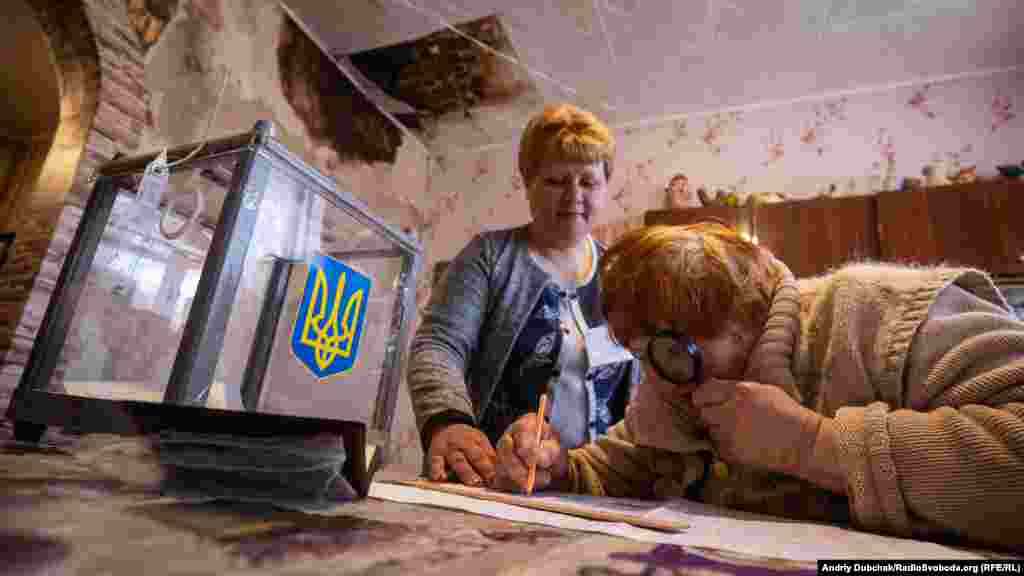 A woman inspects the ballot paper during home voting in the village of Novotroitse in the Donetsk region.