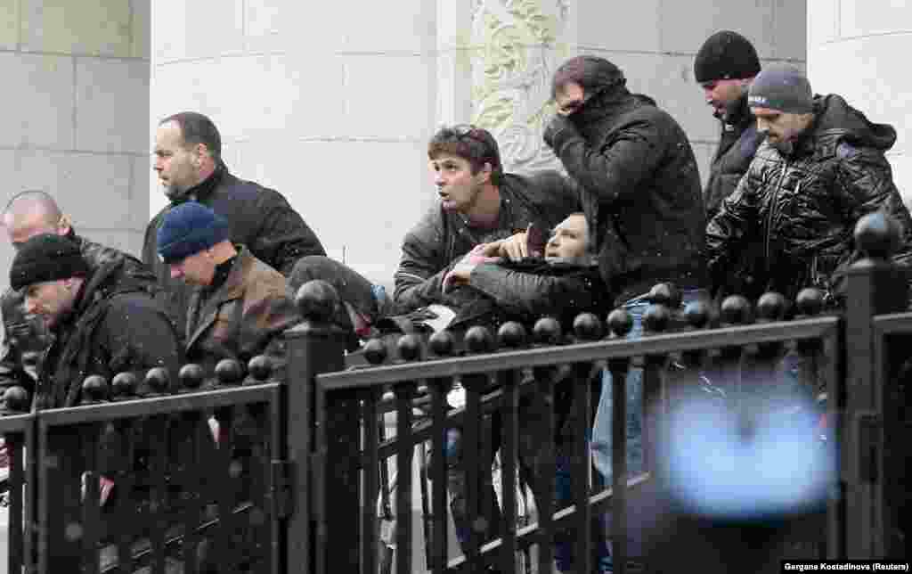 Bodyguards carry Zlatomir Ivanov (center) after he was shot in front of the central court building in downtown Sofia. An unidentified gunman shot the Bulgarian crime boss, nicknamed "The Beret," four times in his legs, arm, and stomach as he was about to enter the central court building. He and a bodyguard were taken to the hospital. (Reuters/Gergana Kostadinova)