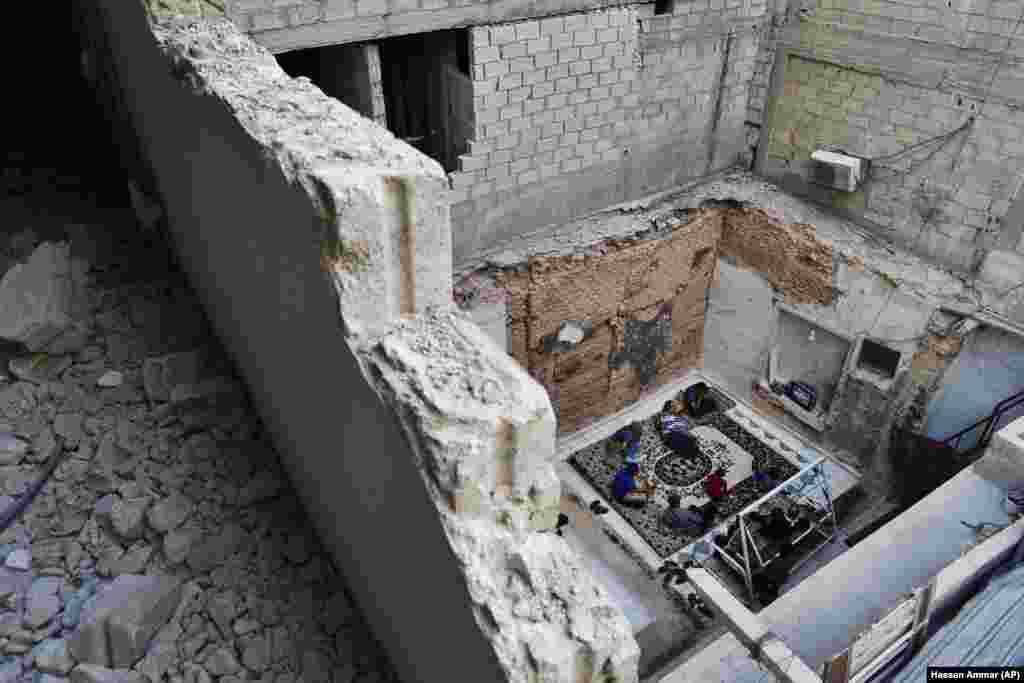 Syrians watch the World Cup soccer final match between France and Croatia in their home, which was partially destroyed by the war, leaving two of its rooms without a ceiling, in the town of Ain Terma, in the Eastern Ghouta suburb of Damascus. (AP/Hassan Ammar)