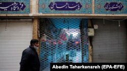 An Iranian man wearing a face mask walks past a closed shopping arcade at Tajrish bazaar, in Tehran, April 10, 2020