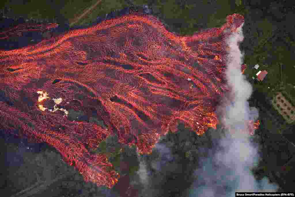 O casa arde, în timp ce un șuvoi de lavă care se mișcă rapid, mistuie tot ce-i stă în cale în Pahoa, Hawaii, pe 19 mai. Erupția vulcanului Kilauea a fost cea mai mare din ultimele decenii, distrugând mai mult de 40 de case și determinând evacuarea a mii de oameni. (epa-EFE / Bruce Omori)