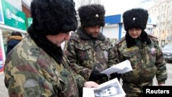 In central Volgograd, Russian Cossacks look at portraits of people suspected of involvement in terrorist acts.