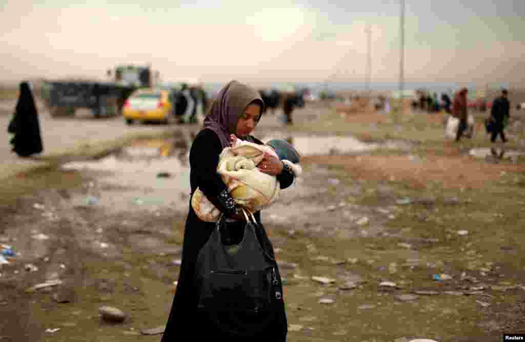 A displaced Iraqi woman carries her baby after fleeing the battle between Iraqi rapid-response forces and Islamic State militants near Mosul. (Reuters/Ahmed Jadallah)