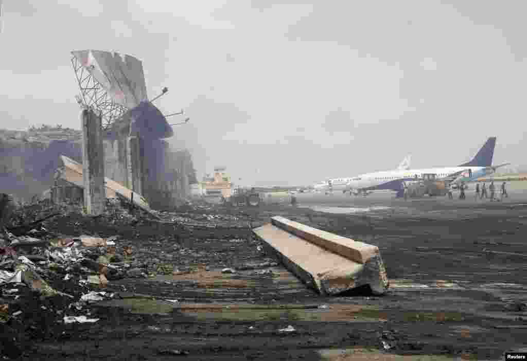 Planes stand near a damaged section of Jinnah International Airport in Karachi, Pakistan, on June 10, after an attack by Taliban militants left at least 27 people dead. (Athar Hussain, Reuters)