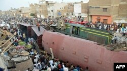 FILE: Onlookers gather around damaged carriages after a passenger train rammed into a goods train in the southern province of Sindh in June 2019.