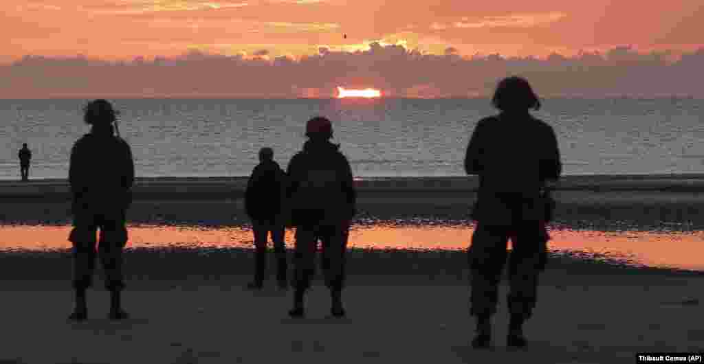 world War II reenactors stand on Omaha Beach, in Normandy, France, at dawn on Thursday, June 6, 2019 during commemorations of the 75th anniversary of D-Day.