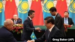 Президент Казахстана Нурсултан Назарбаев (слева на заднем плане) и лидер Китая Си Цзиньпин наблюдают за церемонией заключения двусторонних соглашений. Пекин, 7 июня 2018 года.