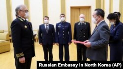 Посол России в Северной Корее Александр Мацегора (слева) передает северокорейскому чиновнику медаль, которая вручена Ким Чен Ыну. 5 мая 2020 года.