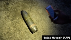 Residents in India-administered Kashmir display what they say is a Pakistani shell that landed on a rooftop.