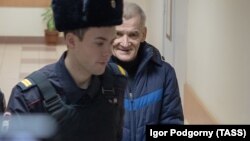 Yury Dmitriyev is escorted to a court hearing in 2019.