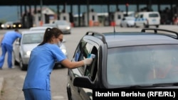 Медицинска сестра проверува темепратура на патници на границата меѓу Косово и Албанија. 