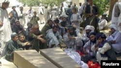 People gather around the coffins of men who were killed in the Kandahar attack.