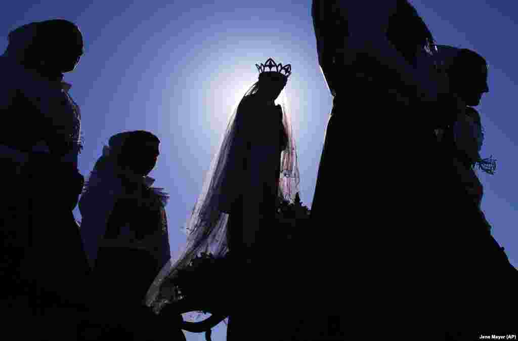 Women dressed in the traditional clothes of the Sorbs carry a statue of the Virgin Mary during a procession in front of the sun in Rosenthal, Germany, on May 21.&nbsp;(AP/Jens Meyer)