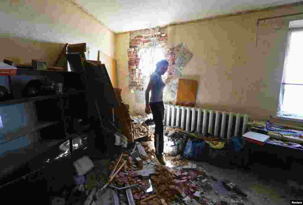 Local resident Tatyana Markova walks inside a house damaged by shelling in the eastern Ukrainian city of Slovyansk on July 1. (Reuters/Shamil Zhumatov)