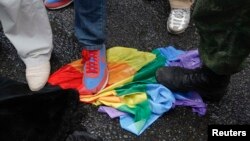 Анти-гей-активисты топчут флаг цвета радуги, символизирующий борьбу за права ЛГБТ-сообщества. Иллюстративное фото.