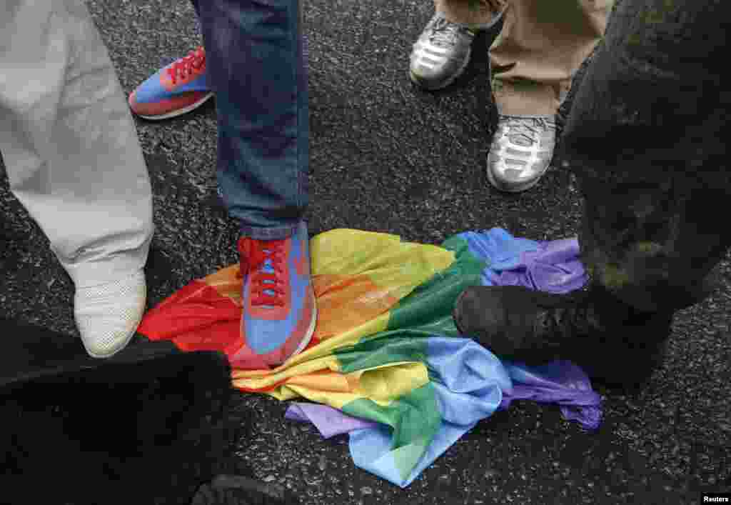 Antigay rights activists trample on a rainbow flag during a protest by gay-rights activists.