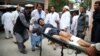 People carry a man who was injured in a suicide bomb attack at an election-campaign rally in eastern Afghanistan's Kama district on October 2. 