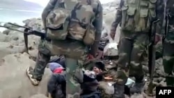 Солдаты сирийской армии перед трупами мирных жителей в провинции Хомс
