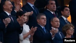 Ձախից՝ աջ. Ադրբեջանի նախագահ Իլհամ Ալիևը՝ կնոջ հետ, Միջազգային օլիմպիական կոմիտեի նախագահ Թոմաս Բախը, Ռուսաստանի նախագահ Վլադիմիր Պուտինը Եվրոպական խաղերի բացման արարողության ժամանակ, Բաքու, 12-ը հունիսի, 2015 թ․
